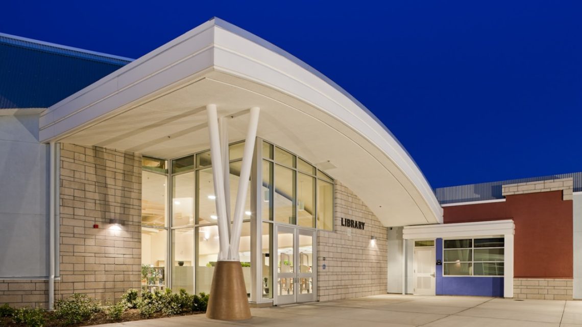 Dublin High School library, western entry at dusk, with the exterior and interior surfaces illuminated.