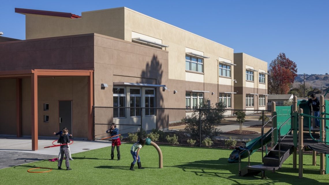 Playyard with kids (model releases available) -South side of school exterior inm the background