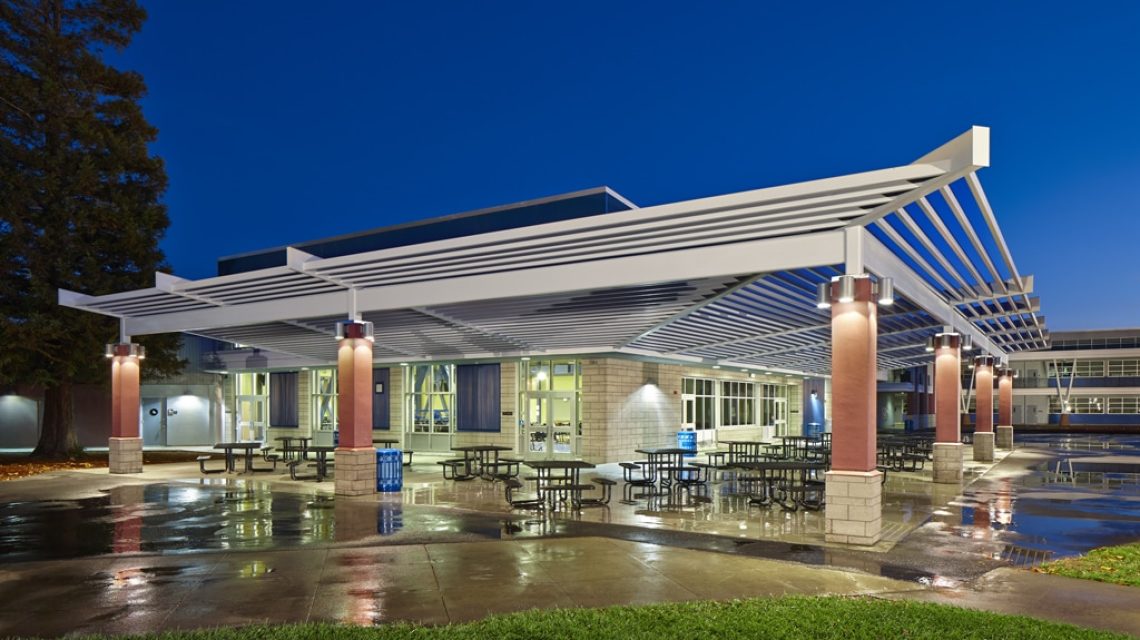 An abolique view of the new DUblin High Schol student union withthe exterior surfaces and th eiterior space illminated at dusk.